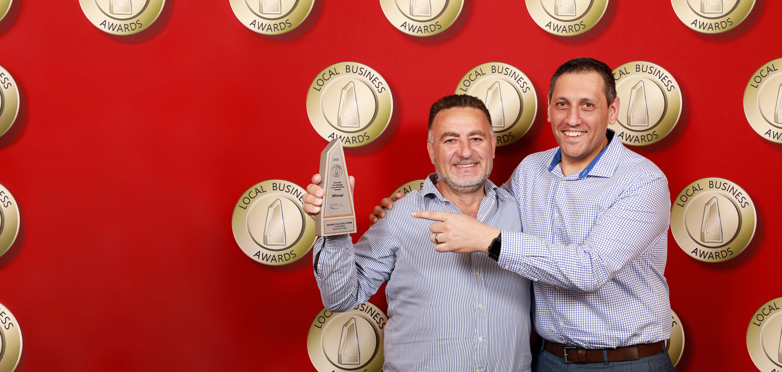 Two men holding local business award