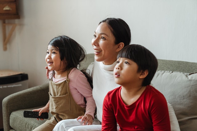 a mom and two kids watching films in home theatre studio